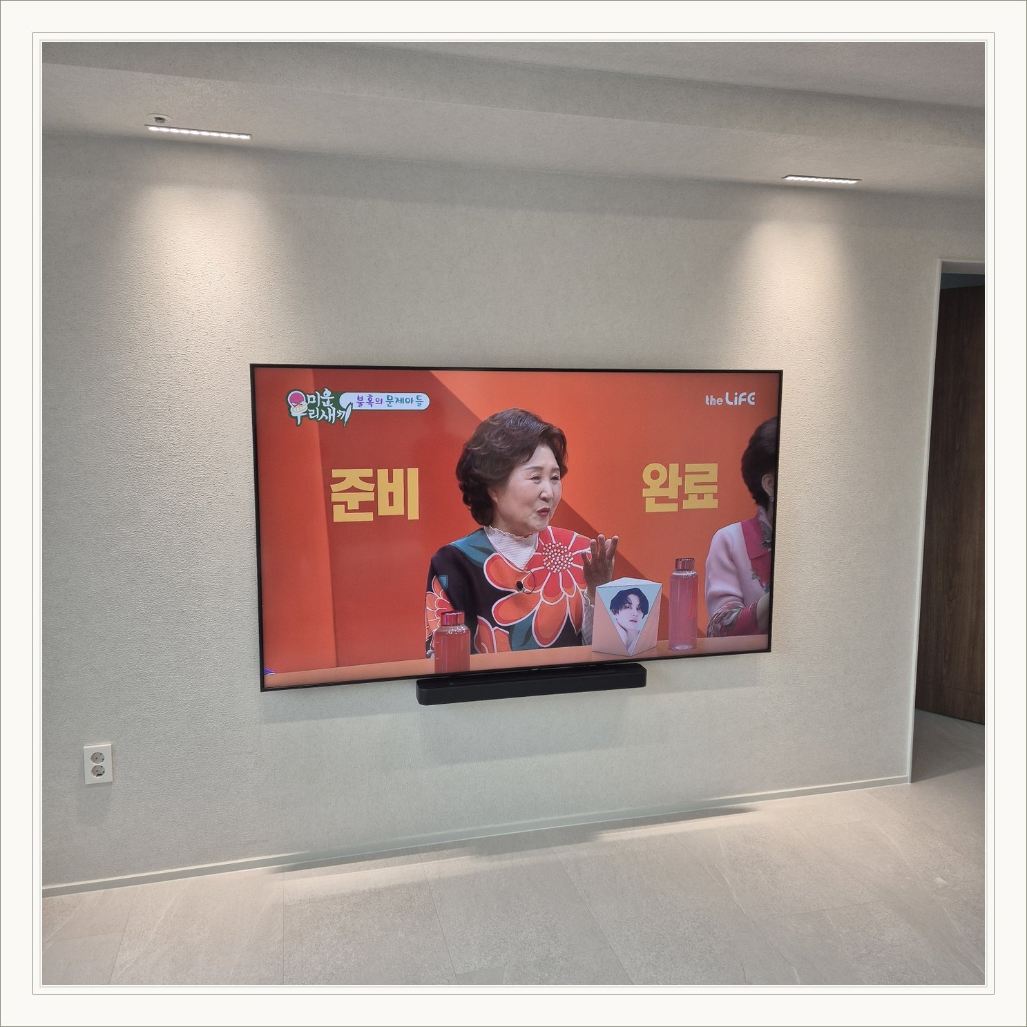 조명이 비추는 미색 벽과 사운드바, 사운드바와 벽면의 간격이 한눈에 들어옵니다