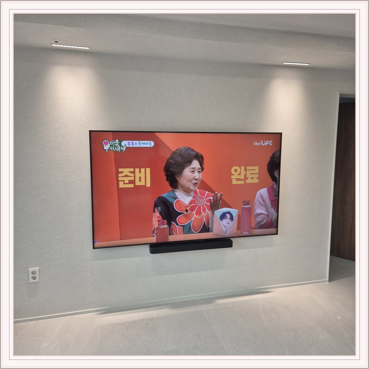 조명이 비추는 미색 벽과 사운드바, 사운드바와 벽면의 간격이 한눈에 들어옵니다