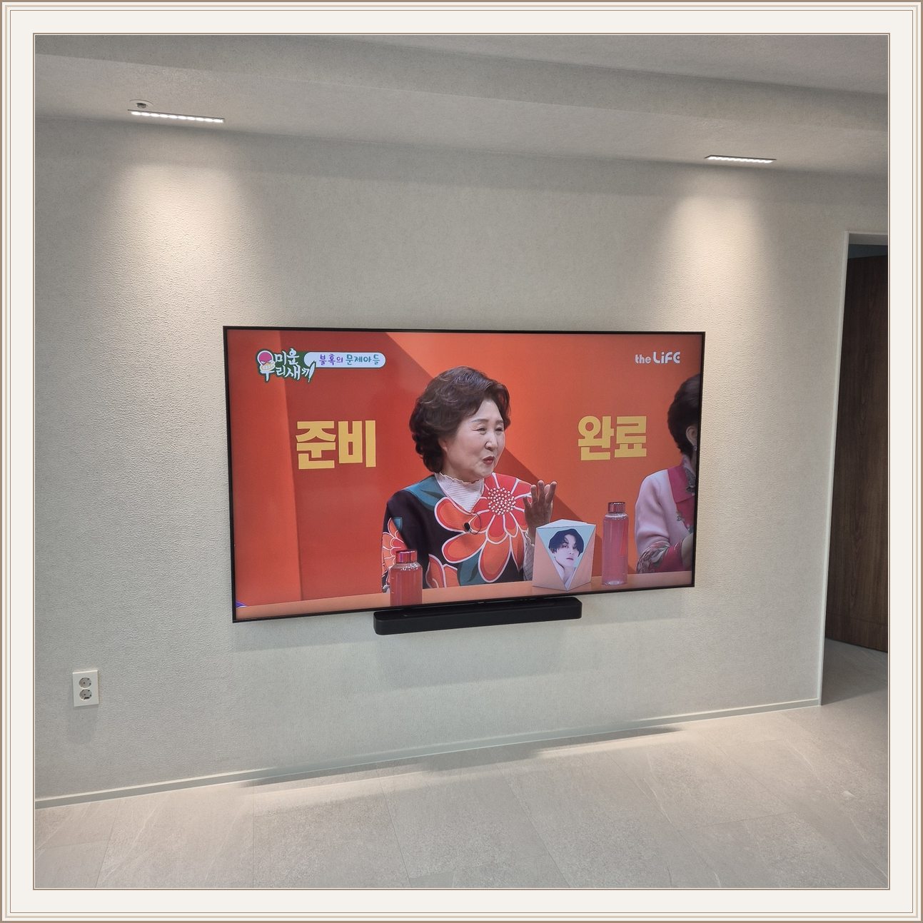 조명이 비추는 미색 벽과 사운드바, 사운드바와 벽면의 간격이 한눈에 들어옵니다